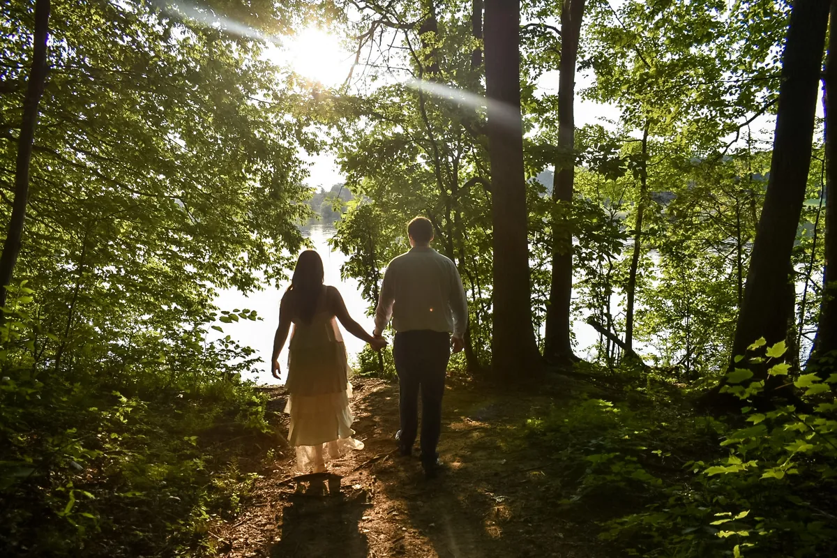 Landon and Alyssa walking hand in hand down a forest path