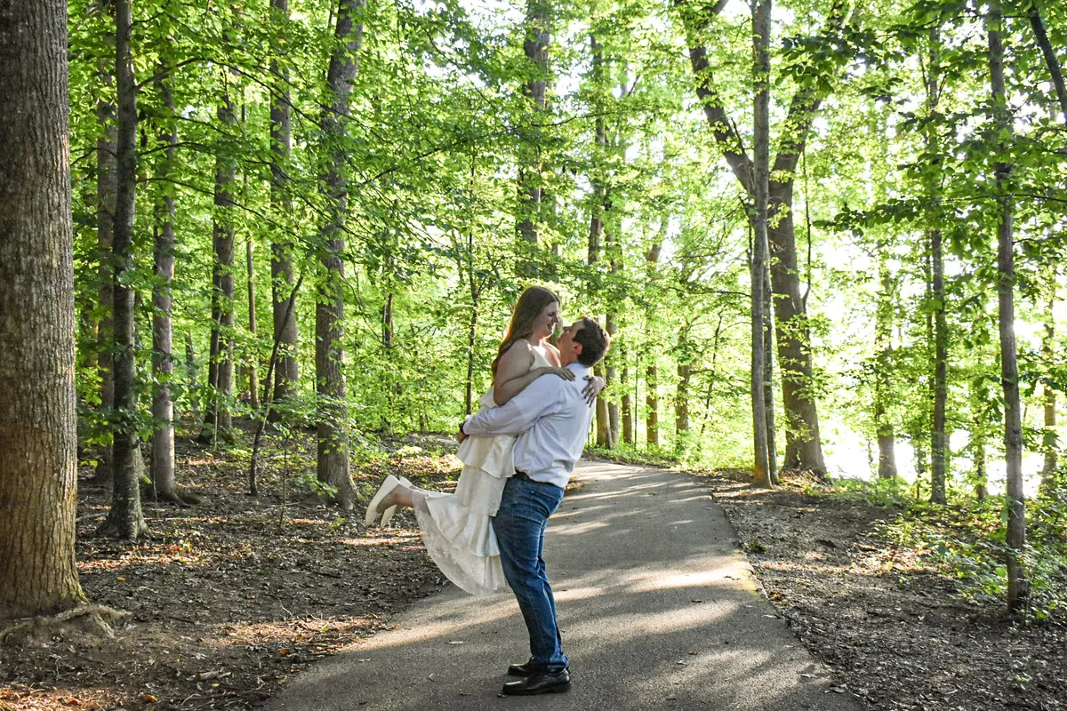 Landon lifting Alyssa off her feet on a forest path
